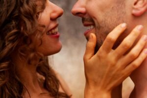 A close-up shot of a smiling couple sharing an intimate moment with hands gently on the face.